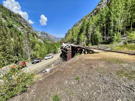 Remains of a wooden mining structure with 4-wheel vehicles on the road below it