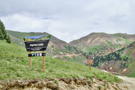 An Alpine Loop road sign with the road curving up to a mountain pass