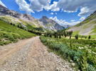 Looking at trail/road down a valley with cliffs in the distance