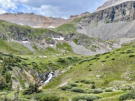 Narrow trail crossing above water cascade with cliffs in the background