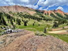 A view down a green mountain valley with a red mountain ridge on the left