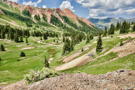 A view down a green mountain valley with a red mountain ridge on the left