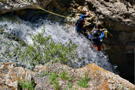 Two climbers roped in on a rock above a roaring river
