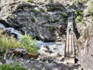 A narrow wooden bridge over a gorge with two climbers walking it