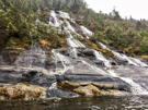 Water falling over rock ledges and cascading down sloped stone into the fjord