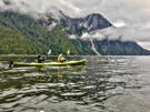 One of the kayaks pauses for the view with the massive granite cliff, the waterfall and the clouds