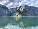 Massive granite  mountains with a valley between feeding down to the green fjord waters