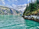 Near the shoreline, the emerald waters are lined with white stone, yellowish ground cover and intense deep green trees