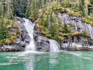 Split waterfall cascading into the fjord’s waters