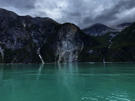 More dramatic granite formations with a green valley leading to a waterfall into the fjord